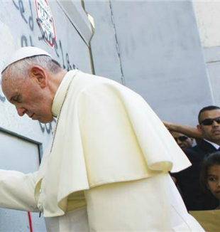 Pope Francis praying in Bethlehem, at the wall that divides Israel and Palestine.